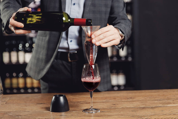 Sommelier gießt Rotwein in Flaschendekanter-Glas, um Belüftungsgetränk herzustellen - Foto, Bild