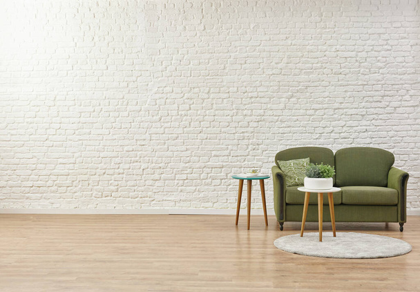 Fehér téglafal háttér, zöld kanapé és otthon tárgy. - Fotó, kép