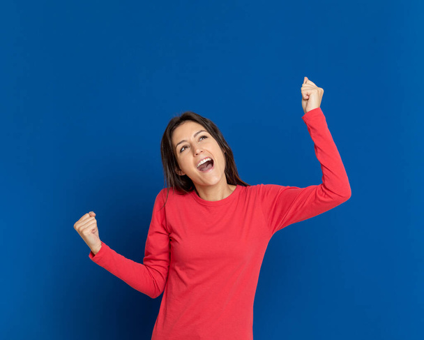 Brunette jonge vrouw draagt een rood T-shirt op een blauwe achtergrond - Foto, afbeelding
