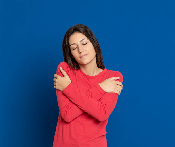 Brunette young woman wearing a red T-shirt on a blue background - Photo, Image