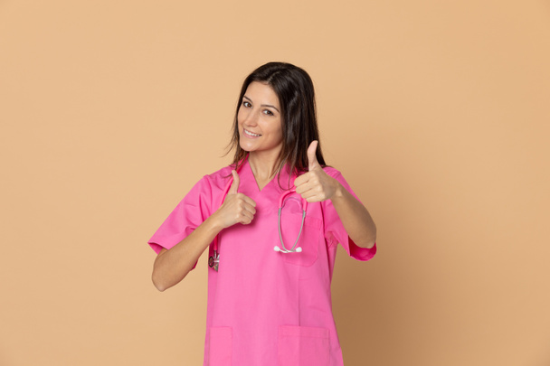 Young doctor with a pink uniform on a blue background - Photo, Image