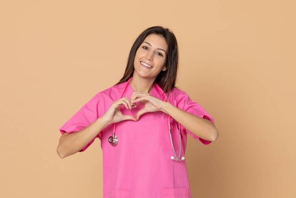 Fiatal orvos rózsaszín egyenruhában, kék háttérrel - Fotó, kép