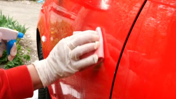 Žena v červeném oblečení myje špinavé červené auto ručně houbou a mýdlovou pěnou. Na dvorku jejího domu. Zavřít. - Záběry, video