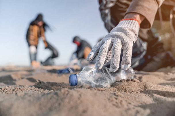 Volunteer man collecting trash on the beach. Ecology concept - Valokuva, kuva