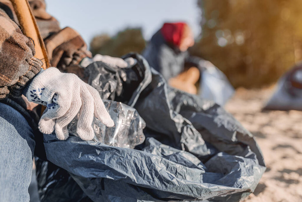 Close up shot of child in gloves collecting plastic bottles on the beach - Fotoğraf, Görsel