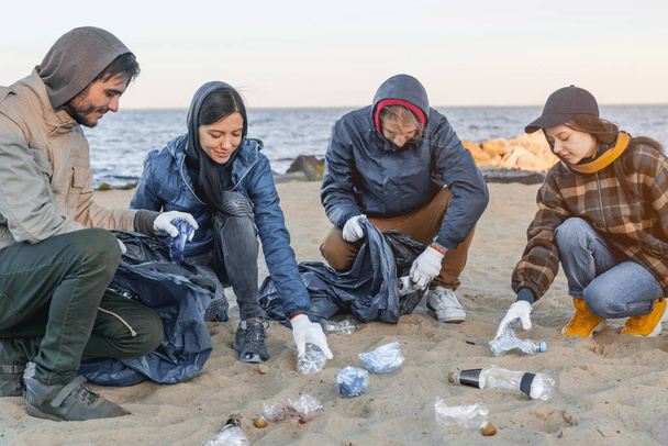 Save the planet. Group of volunteers picking up trash on the beach - Photo, Image