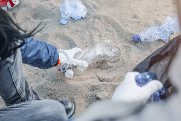 Cropped imafe of girl picking up plastic trash with group of volunteers on the beach - Foto, immagini
