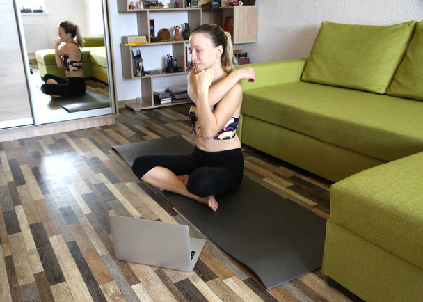 Woman doing yoga at home with laptop internet on line courses. Sportive and healthy lifestyle. Practice yoga during quarantine and self isolation.  - Zdjęcie, obraz