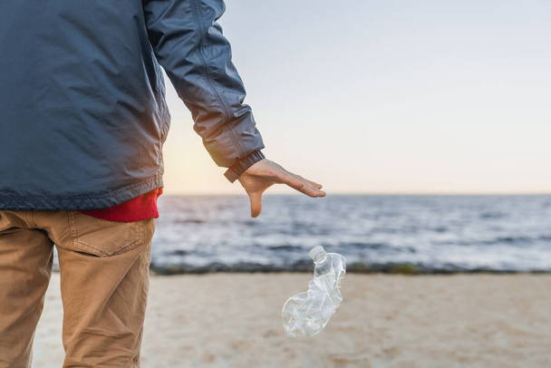 Ecology concept. Man throwing plastic bottle on the beach - Foto, Bild