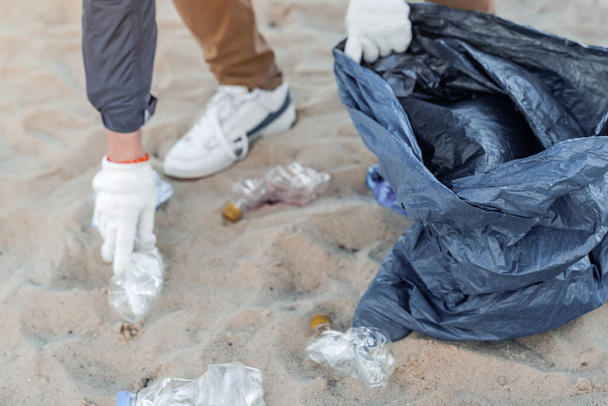 Hands of an activist picking up plastics and trash that pollutes the sea - Fotografie, Obrázek