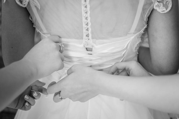 Las damas de honor ayudan a la novia a usar vestido de novia
 - Foto, Imagen
