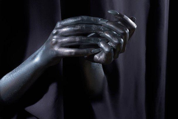 two beautiful mans hands in silver paint on a black background - Фото, зображення