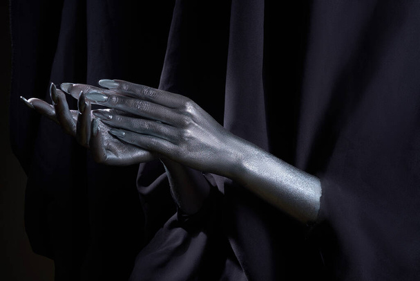 two beautiful mans hands in silver paint on a black background - Foto, Imagen