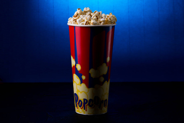 Volle Popcorn-Eimerbox auf dunkelblauem Hintergrund. - Foto, Bild