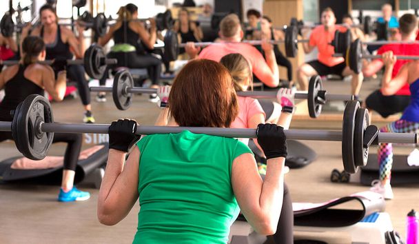 Frauen machen energiegeladene Übungen im Gruppen-Fitness-Kurs. - Foto, Bild