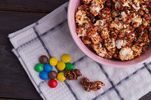 Deliziosi popcorn al caramello fatti in casa con bottoni colorati su tovagliolo bianco
. - Foto, immagini