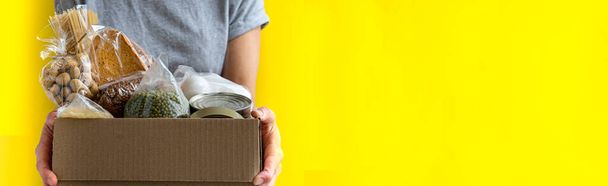 Dobrovolník drží dárcovskou krabici s jídlem pro potřebné lidi. - Fotografie, Obrázek
