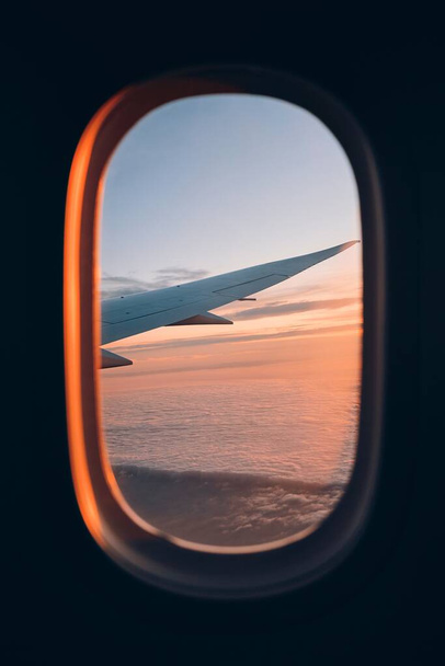 View from window of airplane during flight above clouds at beautiful sunset. Selective focus on wing. - Foto, Imagem