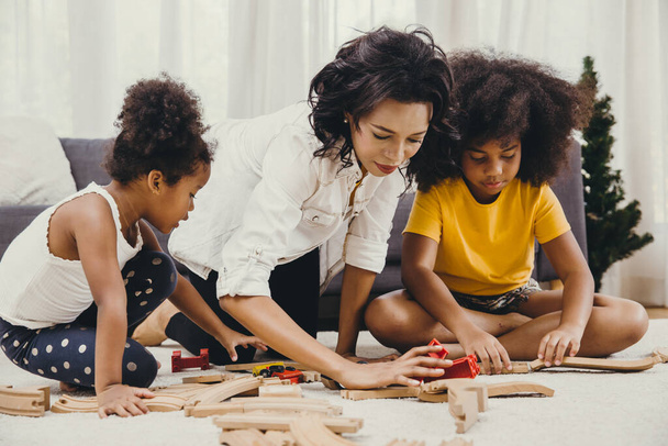 Madre genitore che gioca con i bambini imparando a risolvere puzzle giocattolo a casa appartamento. bambinaia alla ricerca o assistenza all'infanzia in salotto persone di colore
. - Foto, immagini