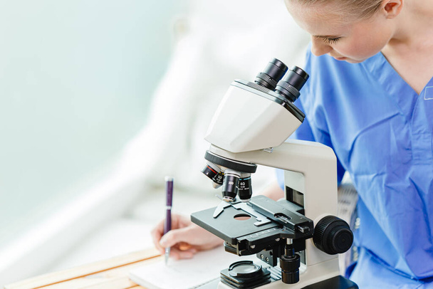 Молодий підліток докторант медичного університету працює над вивченням вірусної вакцини в шкільній лабораторії з мікроскопом
. - Фото, зображення