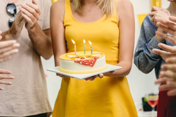 Gros plan femme avec gâteau d'anniversaire dans la fête autour avec des amis applaudir sa chanson de célébration d'anniversaire
. - Photo, image