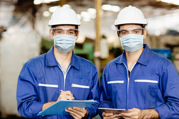 業界の男性労働者は、 Covid-19ウイルス空気塵の汚染を防止し、健康のために工場で働くサービス中にフェイスマスクを着用します。. - 写真・画像