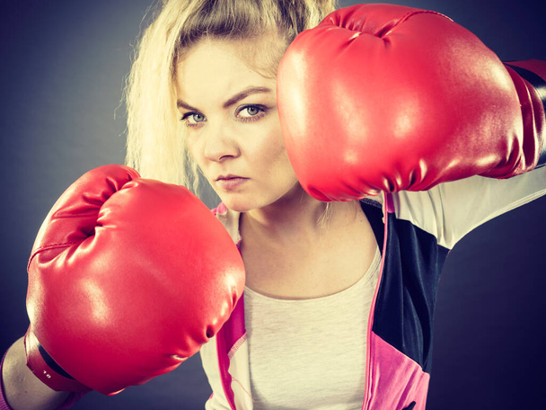 Kırmızı boks eldiveni giyen, kavgacı, kararlı, sportif bir kadın. Stüdyo çekimi koyu arkaplanda. - Fotoğraf, Görsel