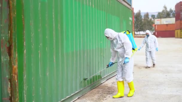 Lidé v ochranných oblecích sprej dezinfekční chemikálie na nákladní kontejner, aby se zabránilo šíření koronaviru. - Záběry, video