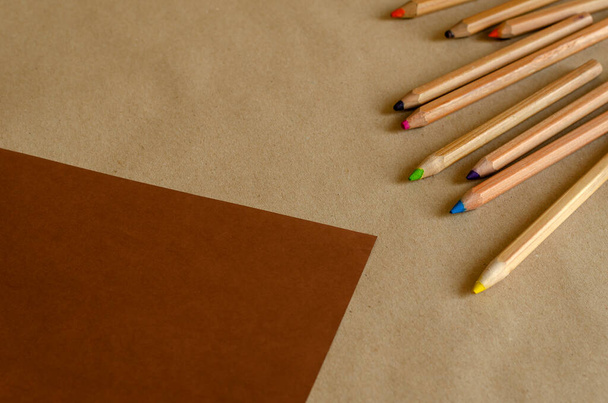 Buntstifte aus Holz auf zweifarbigem Hintergrund. Ein Satz gebrauchter Bleistifte zufällig auf einem braun-beigen Hintergrund. Auf Augenhöhe schießen. Selektiver Fokus. Nahaufnahme. - Foto, Bild