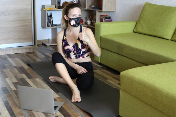 Woman wearing  cotton face mask doing yoga at home. Sportive and healthy lifestyle. Practice yoga during quarantine and self isolation.  - Fotoğraf, Görsel