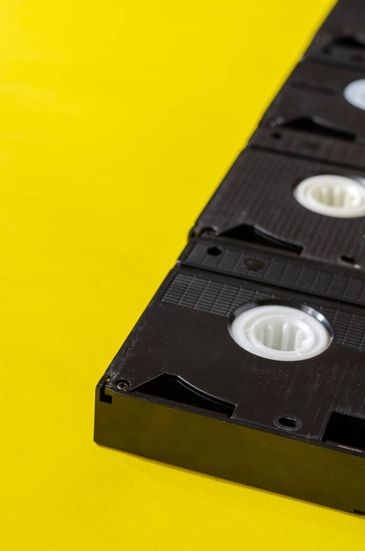 Renkli arka planda eski video kasetler. Sarı arka planda birkaç kaset var. Yaratıcı bir geçmiş. Yakın plan. Uzayı kopyala Seçici odak. - Fotoğraf, Görsel