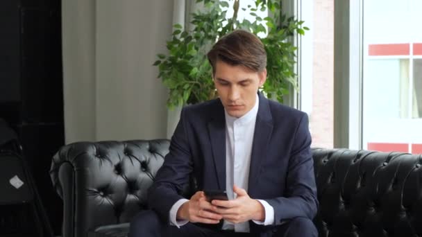 Relaxed European man using smartphone app. Handsome bearded male businessman mobile office.  - Metraje, vídeo