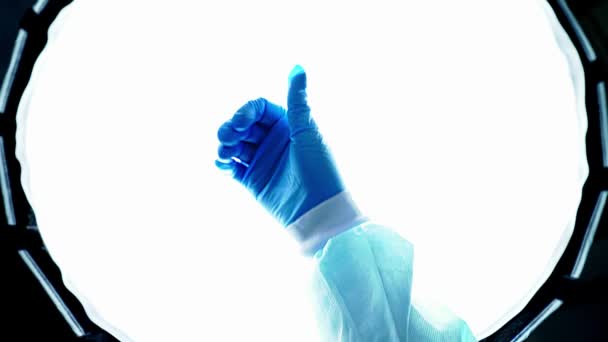 Dokter in blauwe medische handschoenen laat duim omhoog zien. Overwinning van de ziekte. De hand van een verpleegster die mensen redt tijdens een epidemie. Bescherm uw handen tegen virussen. Wereldpandemie, wereldwijde crisis. Zoals.... - Video