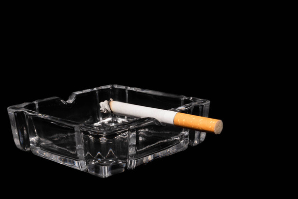 cendrier en verre avec cigare brûlant, fond noir
 - Photo, image