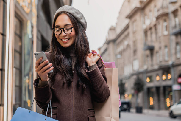 Young asian woman texting while enjoying a day shopping - Foto, imagen