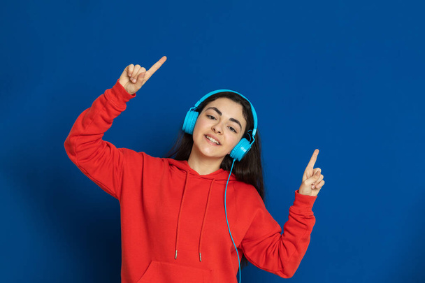 Brunette young girl wearing red jersey on a blue background - Valokuva, kuva