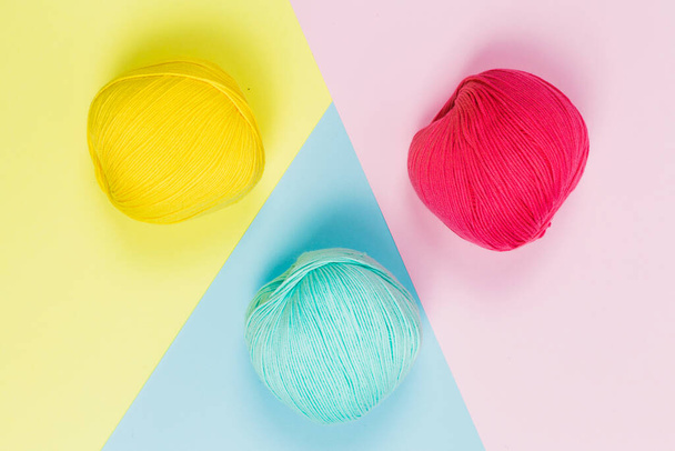Flat lay de bela hortelã verde, coral rosa e amarelo escuro bolas de lã de algodão com fundo de cores pastel geométrico
 - Foto, Imagem