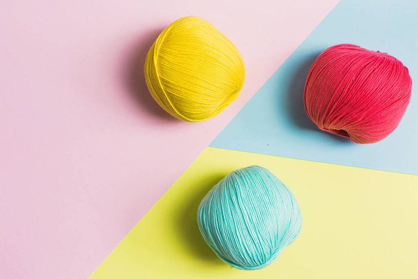 Flat lay of beautiful mint green, coral pink and dark yellow balls of cotton wool with geometrical pastel colors background - Foto, Imagen