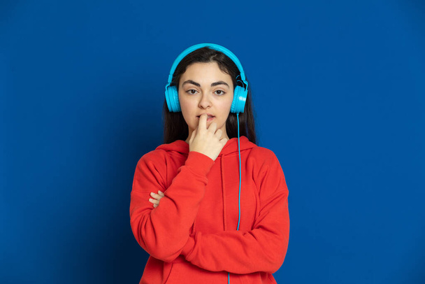 Brunette young girl wearing red jersey on a blue background - Fotó, kép