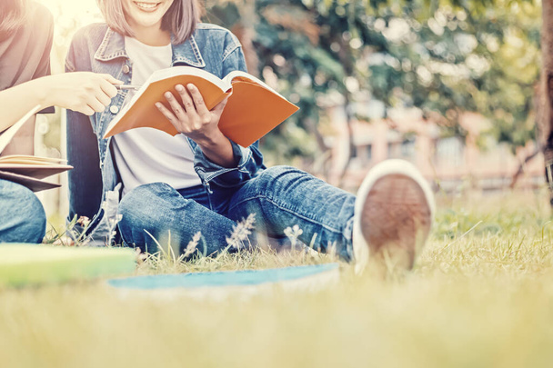 Студенти університету сидять і читають книгу на траві
. - Фото, зображення