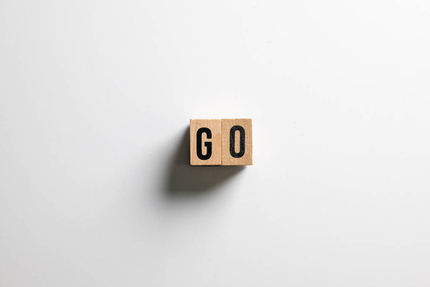 " GO "κείμενο από ξύλινο κύβο σε λευκό φόντο. - Φωτογραφία, εικόνα