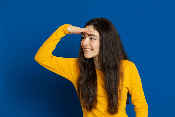 Bruneta mladá dívka na sobě žlutý dres na modrém pozadí - Fotografie, Obrázek
