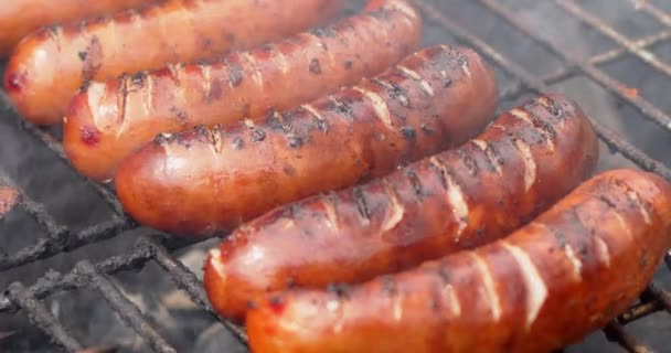 Close up on placend in row on barbecue grill tasty frying sausages. Slow motion video - Footage, Video