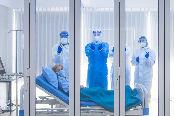 Dortor, pielęgniarka i pacjent patrzący w pomieszczeniu kwarantanny z powodu koronawirusu covid 19. Pacjent zakażony wirusem z ogniskiem choroby w szpitalu z coronavirus covid 19. - Zdjęcie, obraz