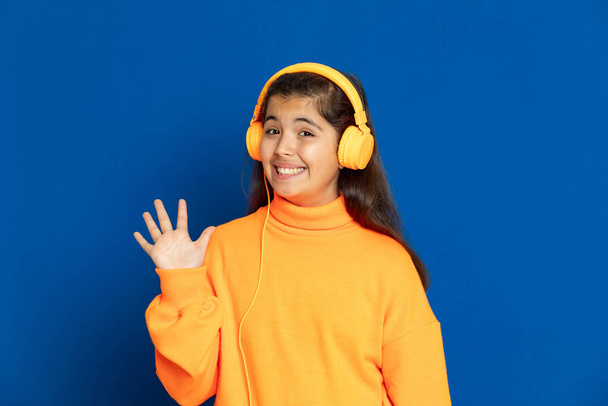 Schattig mooi meisje met gele trui op een blauwe achtergrond - Foto, afbeelding