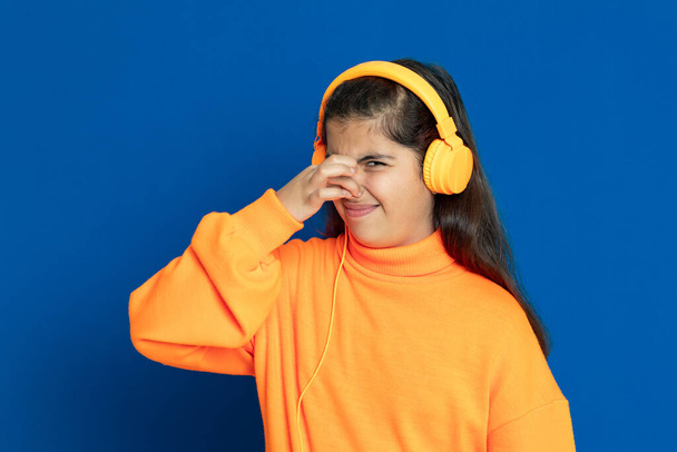Schattig mooi meisje met gele trui op een blauwe achtergrond - Foto, afbeelding