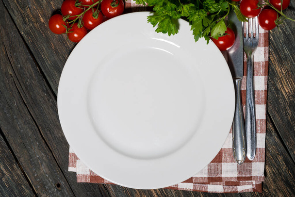 table setting with white plate and vegetables on wooden table, top view horizontal - Photo, image