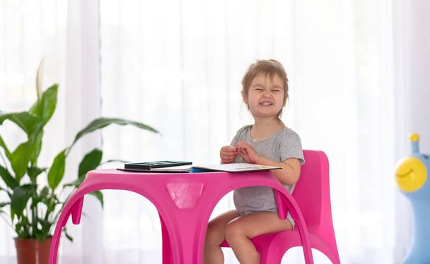 Geconcentreerd schattig 2-jarig meisje speelt thuis met stickers. Quarantaine. Blijf thuis. Binnenactiviteiten. - Foto, afbeelding