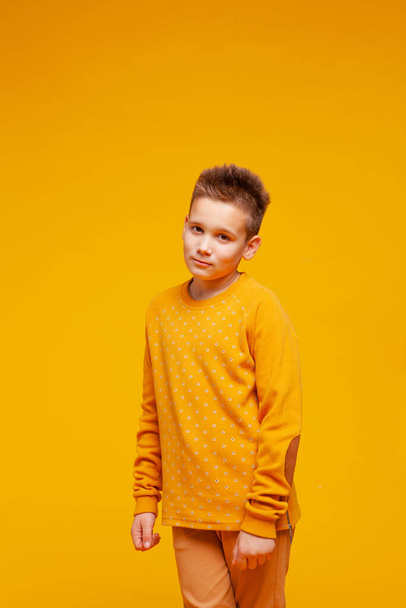 teenager stands on an orange-yellow background  - Fotoğraf, Görsel