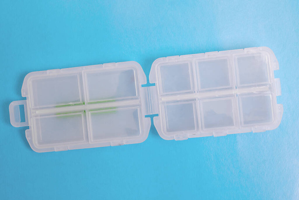 Пластиковый контейнер для таблеток на синем фоне
 - Фото, изображение